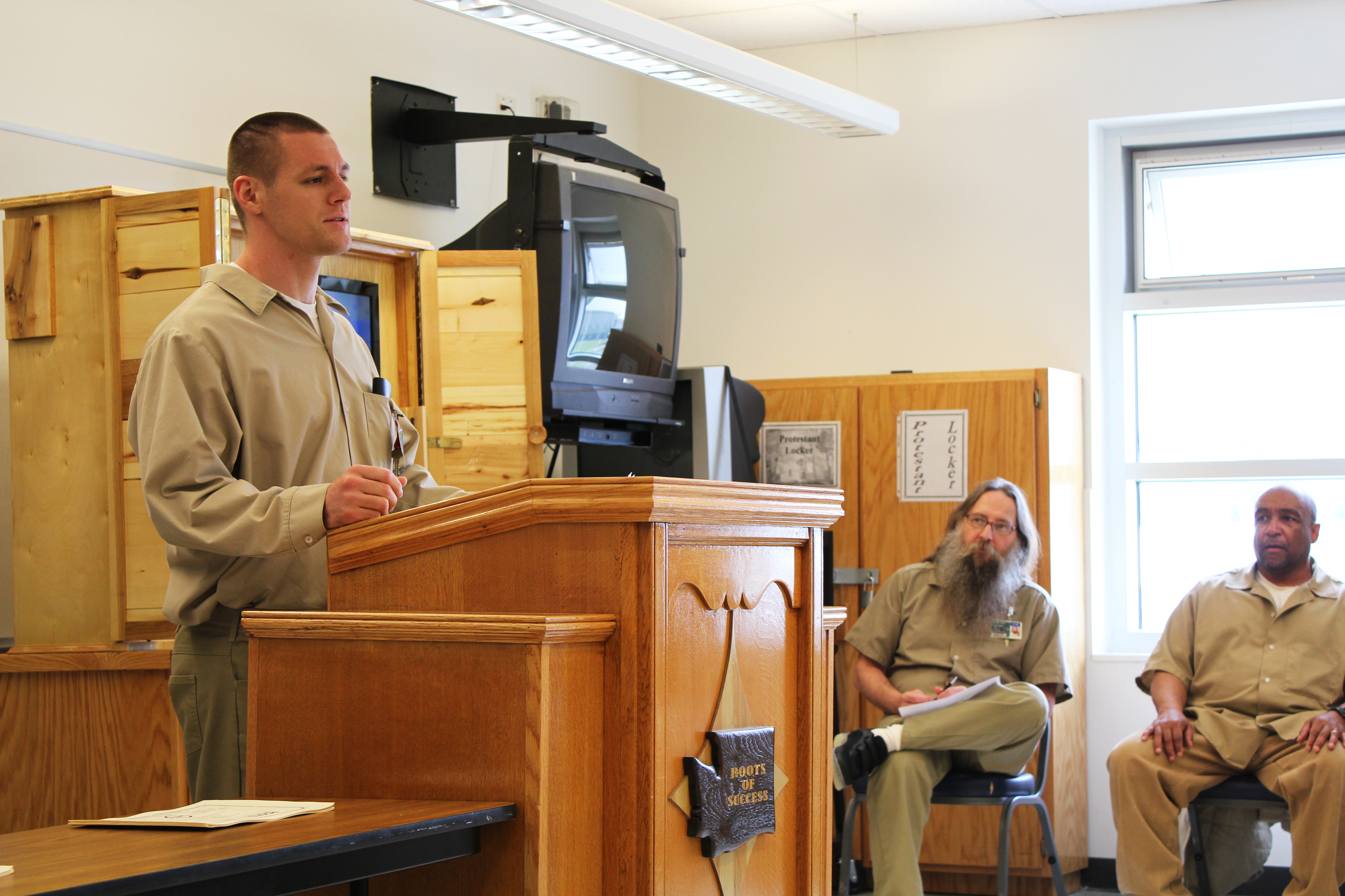 Hankins, member of Stafford’s first Roots of Success cohort, speaks to new graduates while Instructors DuHaime and Mitchell look on