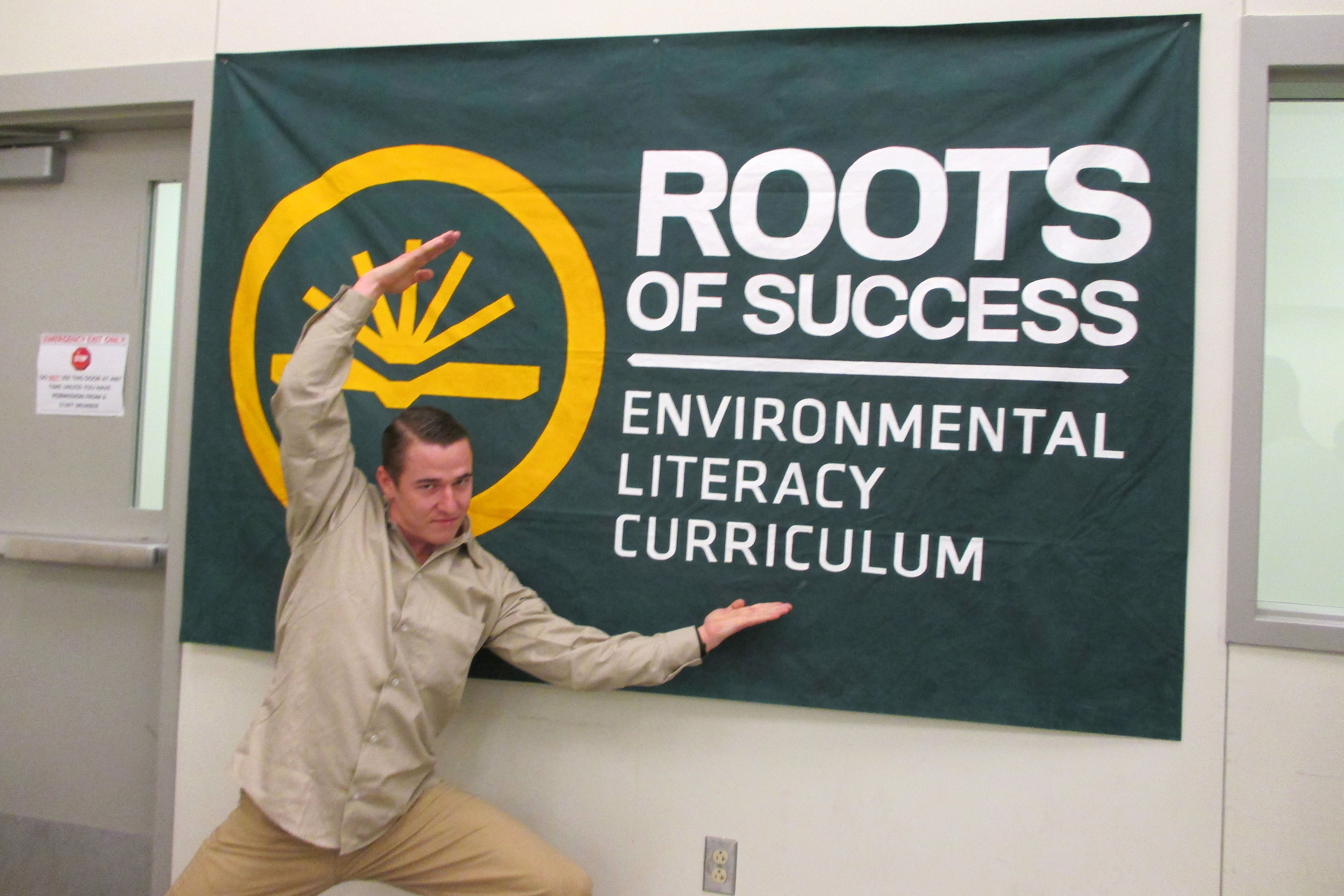 Travis Turley, Roots graduate and graduation speaker, poses in front of CRCC's Roots of Success sign after graduation. Photo by Joslyn Rose Trivett