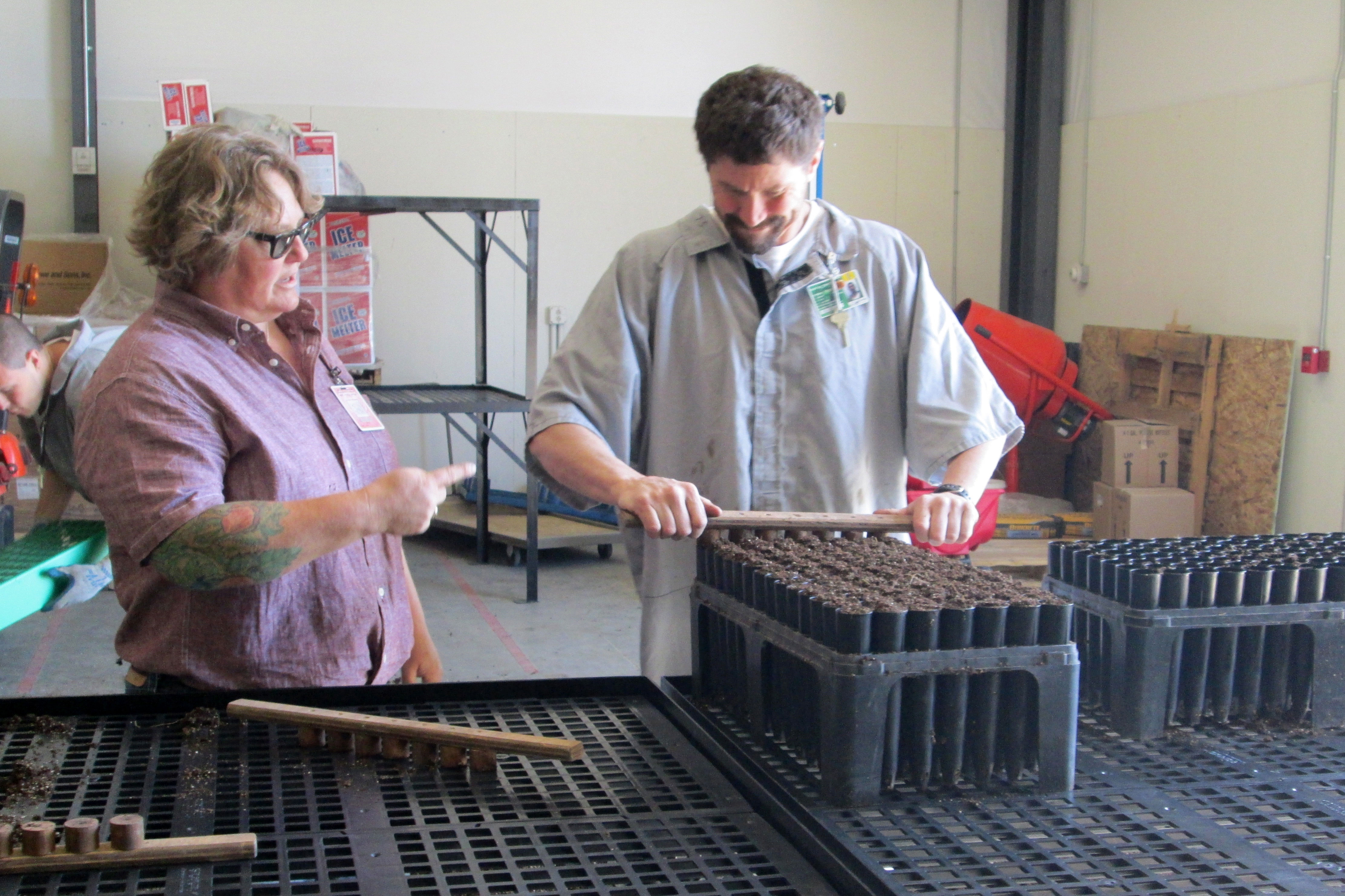 Plant ecologist and horticulture educator Gretchen Grabber works with an inmate technician filling tray for seed sewing. Photo by CRCC staff.